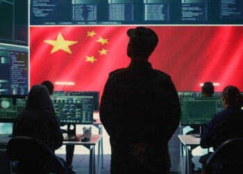 Communist China military personnel in a high tech government hacking room work on stealing state secrets from rival countries in hybrid war. Chinese communist criminals and army exploit advanced technology, inflict fear. Camera B.