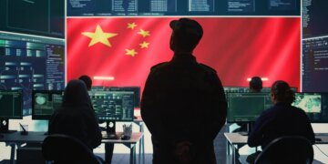 Communist China military personnel in a high tech government hacking room work on stealing state secrets from rival countries in hybrid war. Chinese communist criminals and army exploit advanced technology, inflict fear. Camera B.