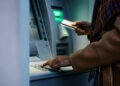 Close up of African American woman entering pin while using ATM machine.
