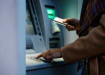 Close up of African American woman entering pin while using ATM machine.