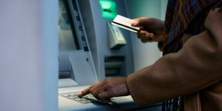 Close up of African American woman entering pin while using ATM machine.