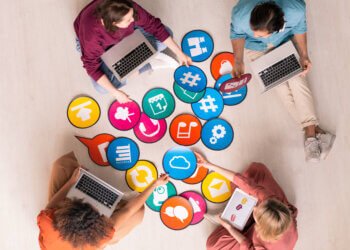 Above view of young social media marketers sitting on floor and using computers while analyzing marketing tools