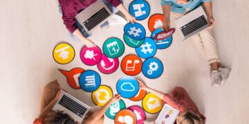 Above view of young social media marketers sitting on floor and using computers while analyzing marketing tools