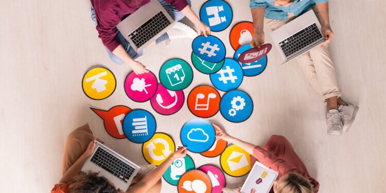 Above view of young social media marketers sitting on floor and using computers while analyzing marketing tools
