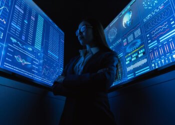 The businesswoman standing near the blue monitor